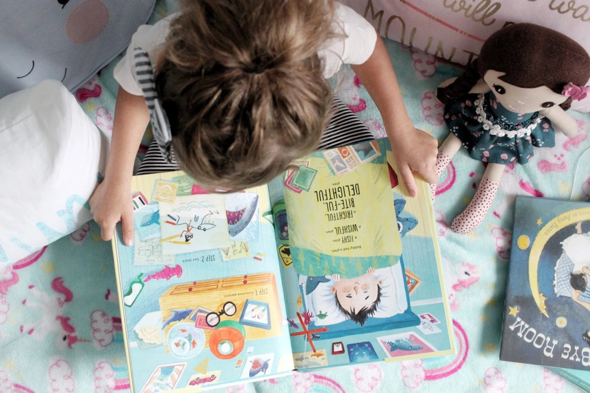 Overhead view of child with two books in their lap